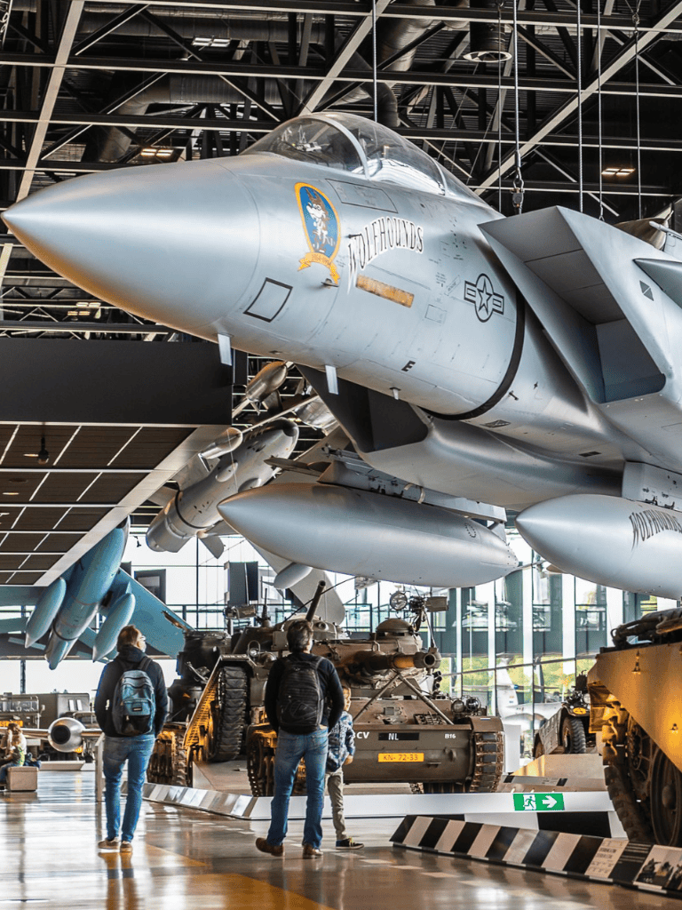 F-22 Raptor stealth fighter jet and military vehicles at an aviation museum exhibit.