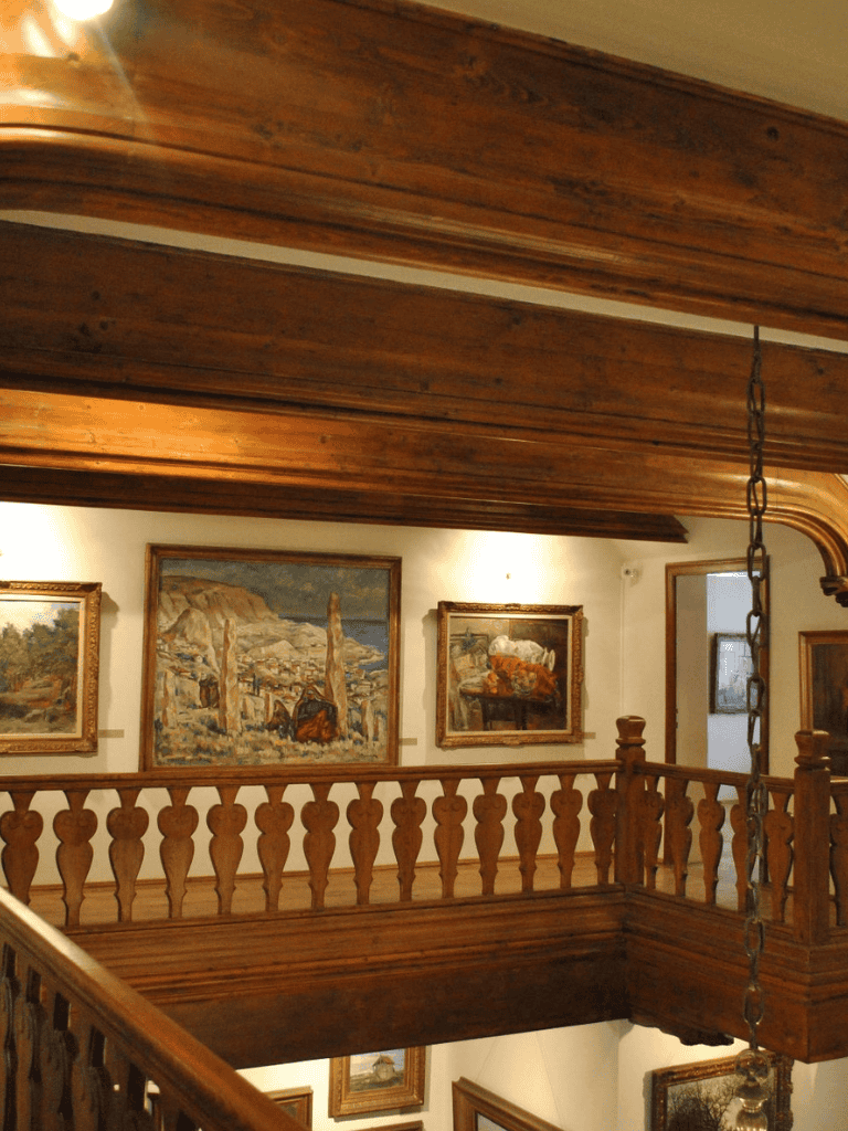 Exhibition hall with classic wooden balcony and landscape paintings for art enthusiasts.