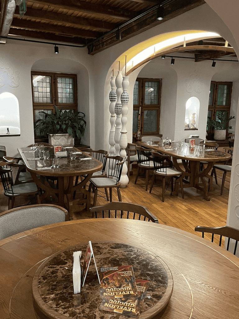 Vintage dining room with wooden tables and chairs, warm lighting, and rustic decor.