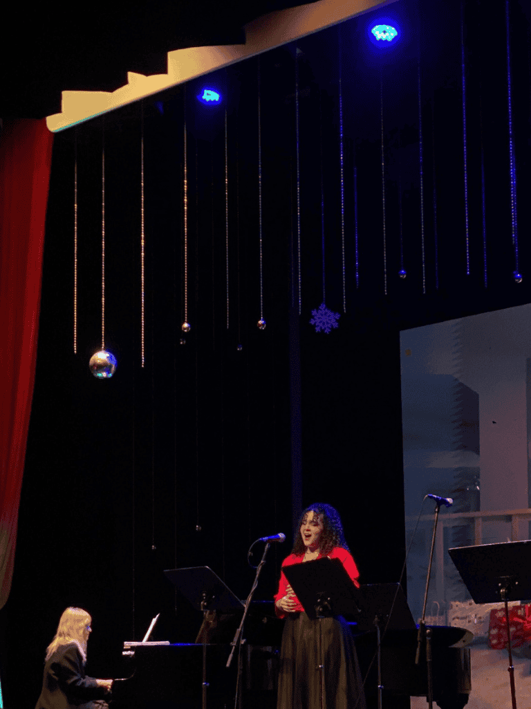 Vocalist performing on stage with Christmas decorations and jazz band, holiday music event, QuestForDirections.