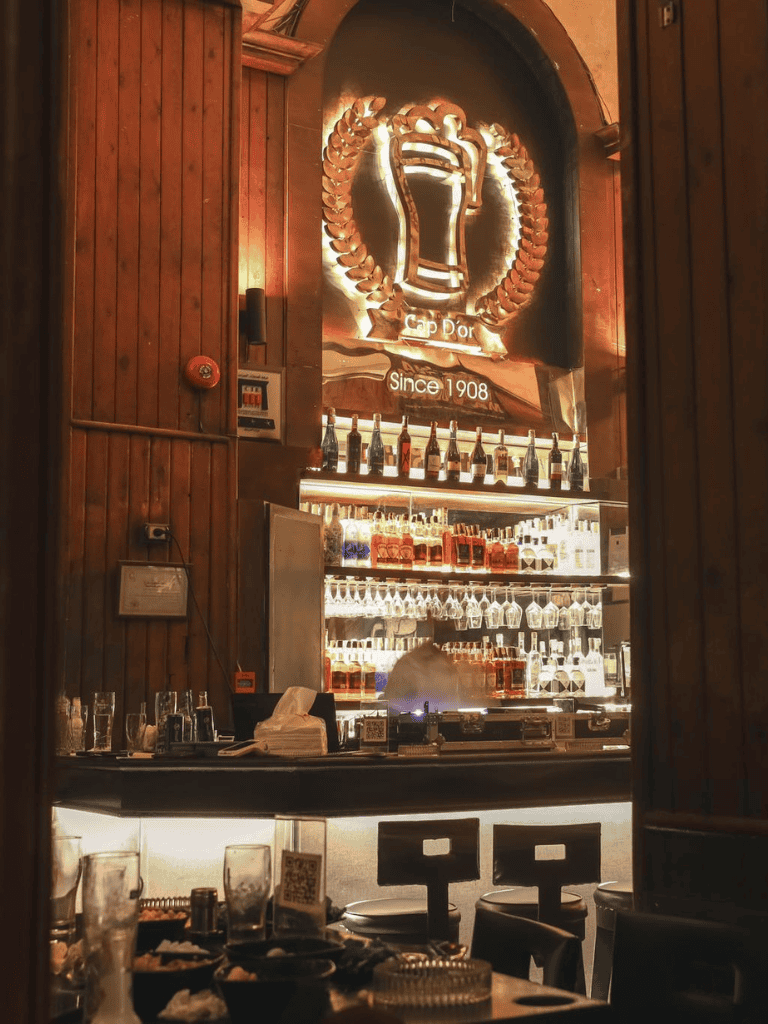 Elegant bar interior with neon beer mug sign and extensive liquor collection - Quest for Directions.