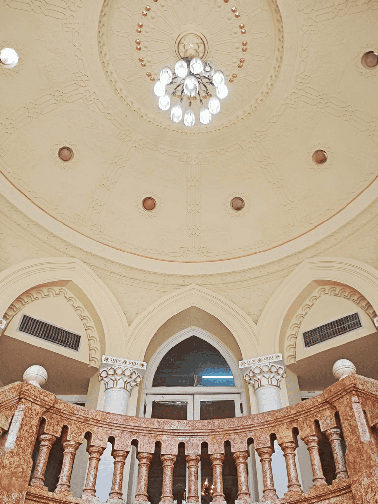 Elegant palace interior with ornate arches and chandelier, showcasing luxurious architecture and design.