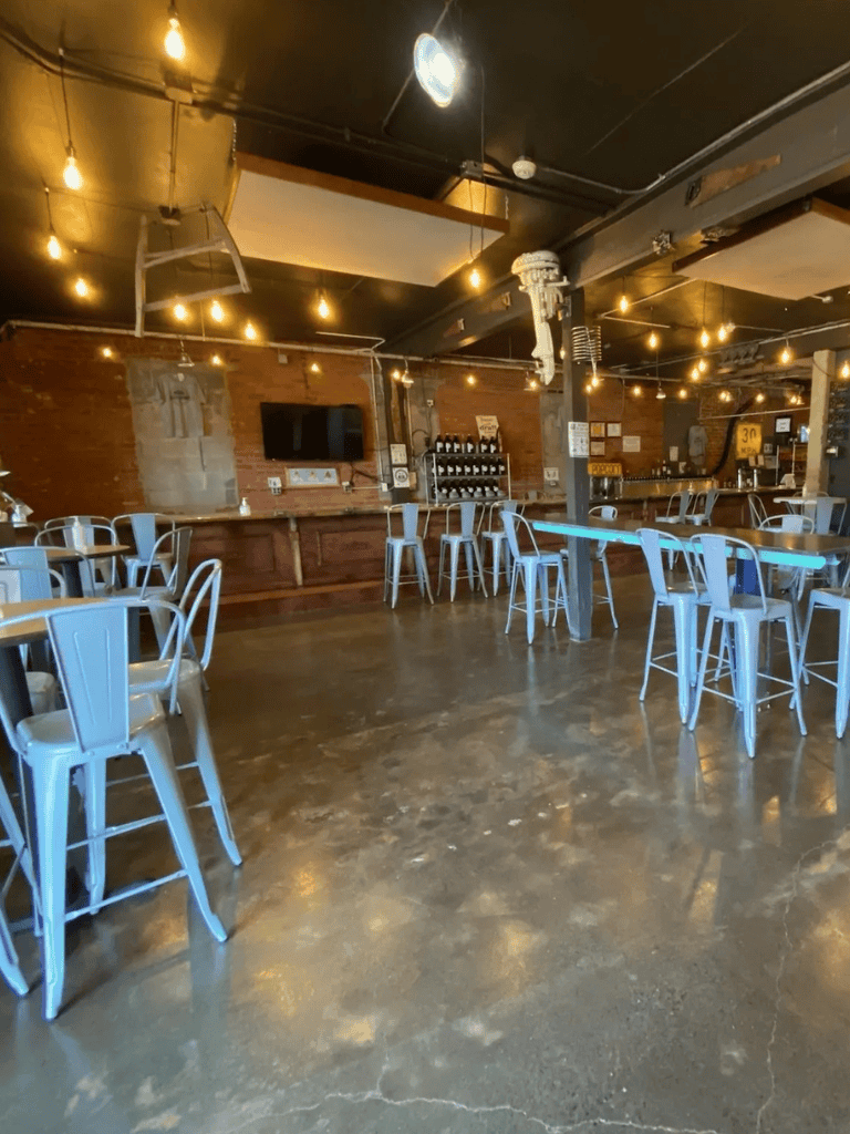Cozy modern restaurant interior with metal chairs, warm lighting, and brick walls, ideal for dining and socializing.