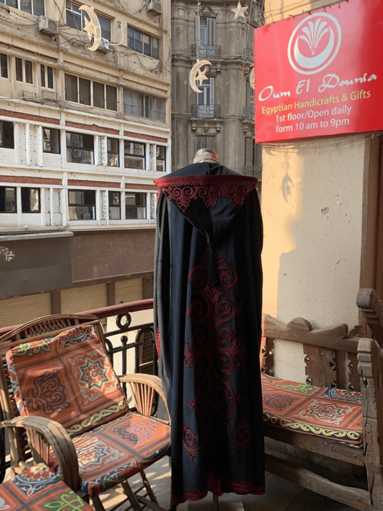 Elegant black and red traditional Egyptian dress displayed on a balcony with courtyard seating.