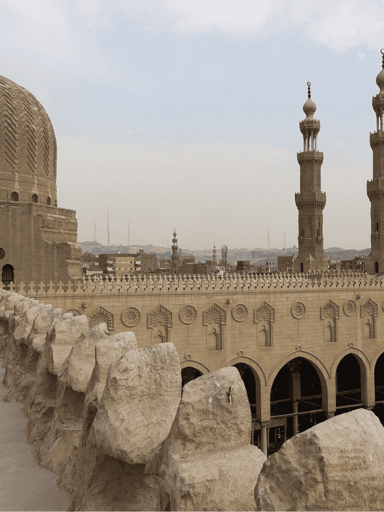 Ancient mosque architecture with minarets and sand-colored stone details in Middle Eastern cityscape.