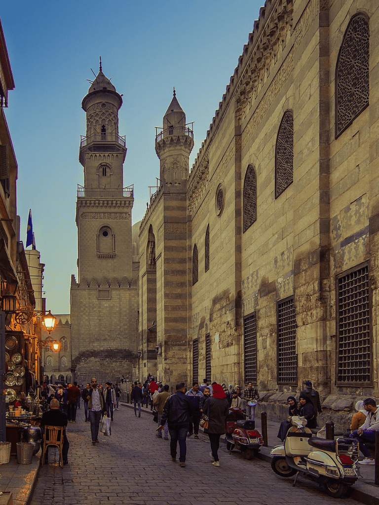 Intricate mosque minarets and bustling street scene in Cairo, Egypt, showcasing Islamic architecture and vibrant local culture.