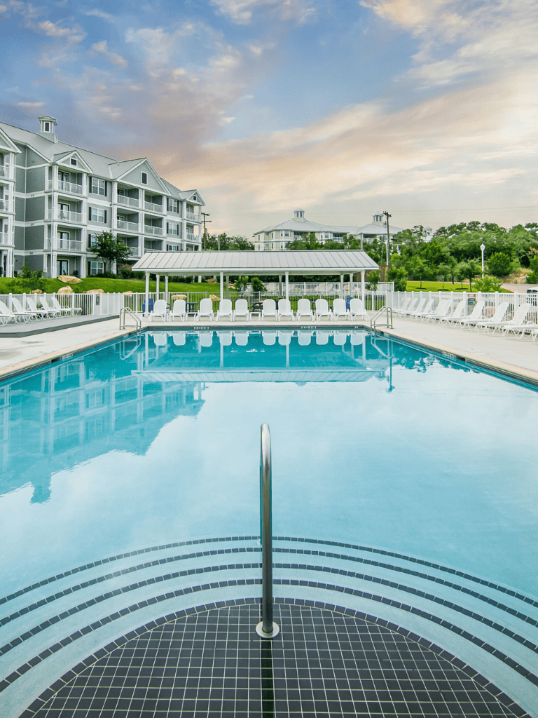 Modern outdoor swimming pool with lounge chairs and surrounding residential buildings, perfect for relaxation and leisure.