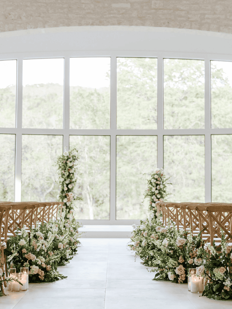 Elegant wedding ceremony setup with floral aisle decor and large window backdrop | QuestForDirections.