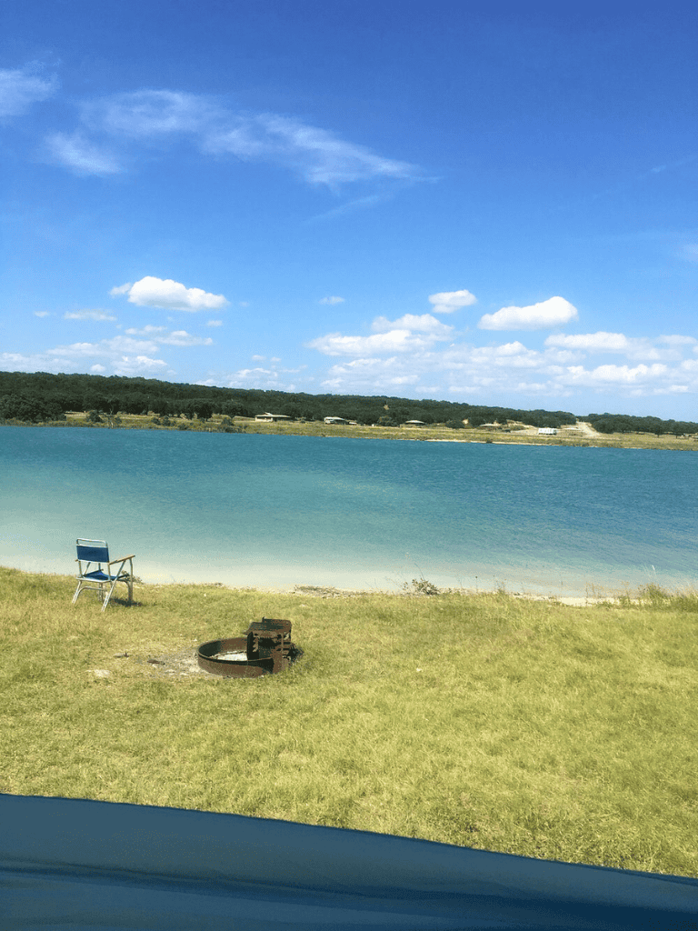 Serene lakeside scene with a chair and fire pit under clear blue sky, perfect for outdoor relaxation and nature exploration.