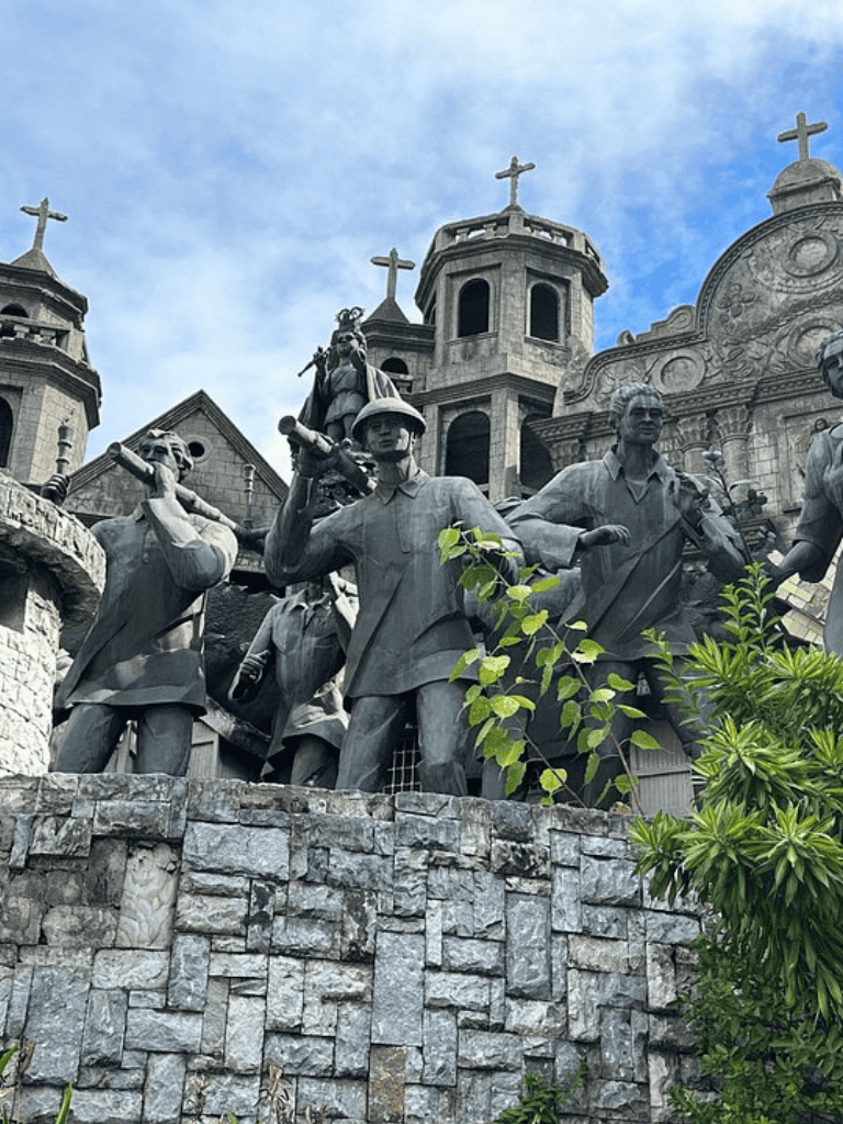 Statue of Filipino heroes on a stone base at the historic church in Philippines.