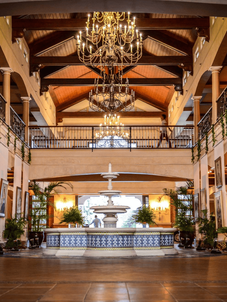 Elegant hotel lobby with chandeliers and a central fountain, offering luxurious ambiance and sophisticated decor.