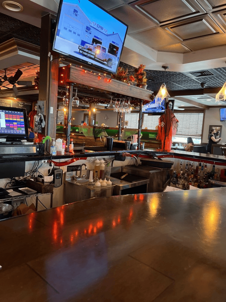 Cozy bar interior with TV screens, festive decorations, and a variety of beverages, perfect for dining and socializing.