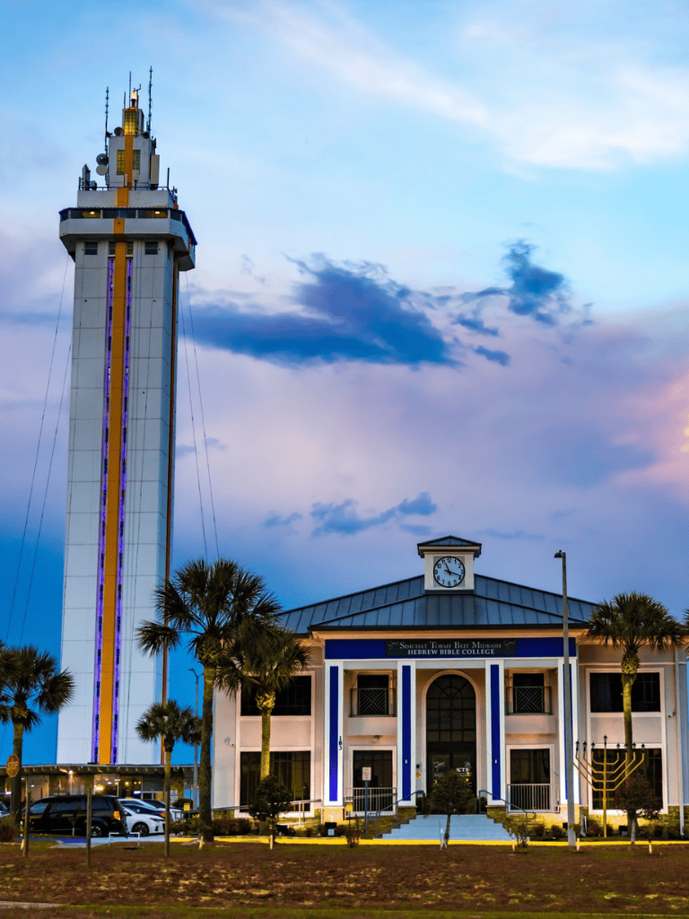 Skyscraper tower near Hebrew Bible College in quest for directions, tall clock tower with sunset sky.