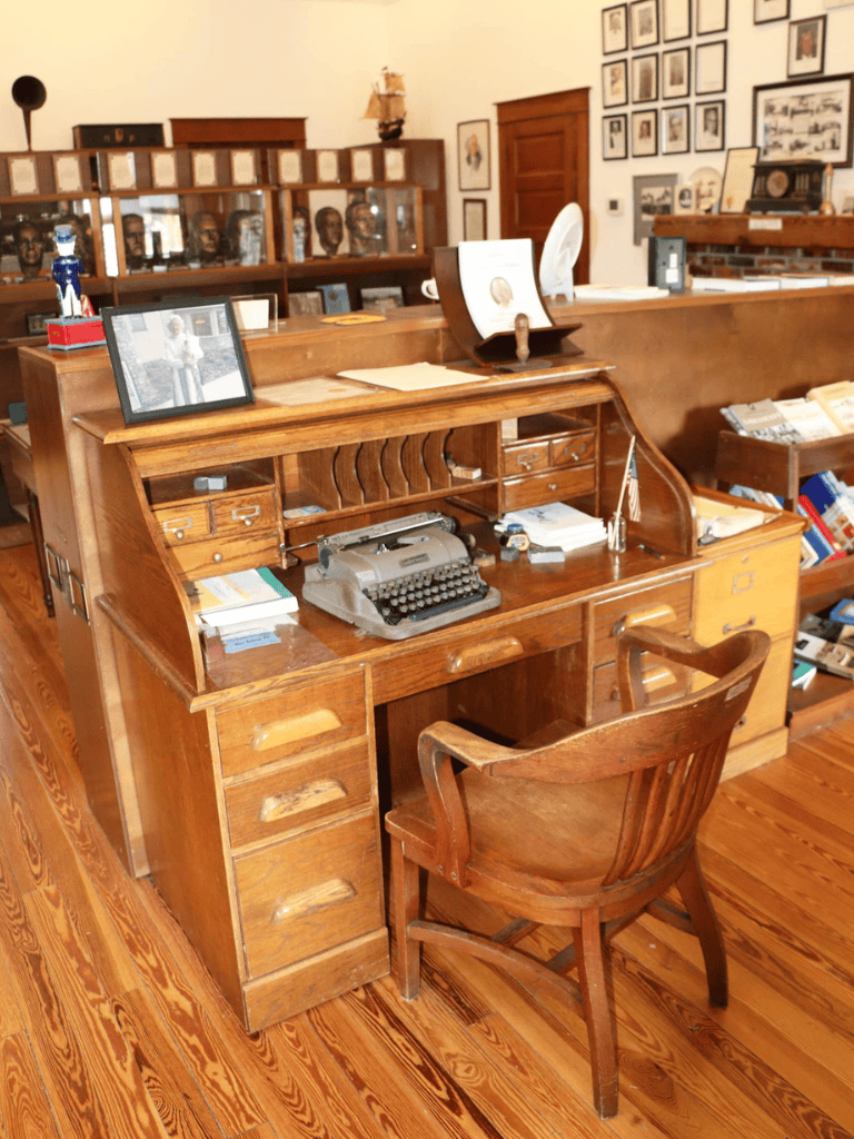 Typewriter on wooden desk in nostalgic office setting with vintage decor.