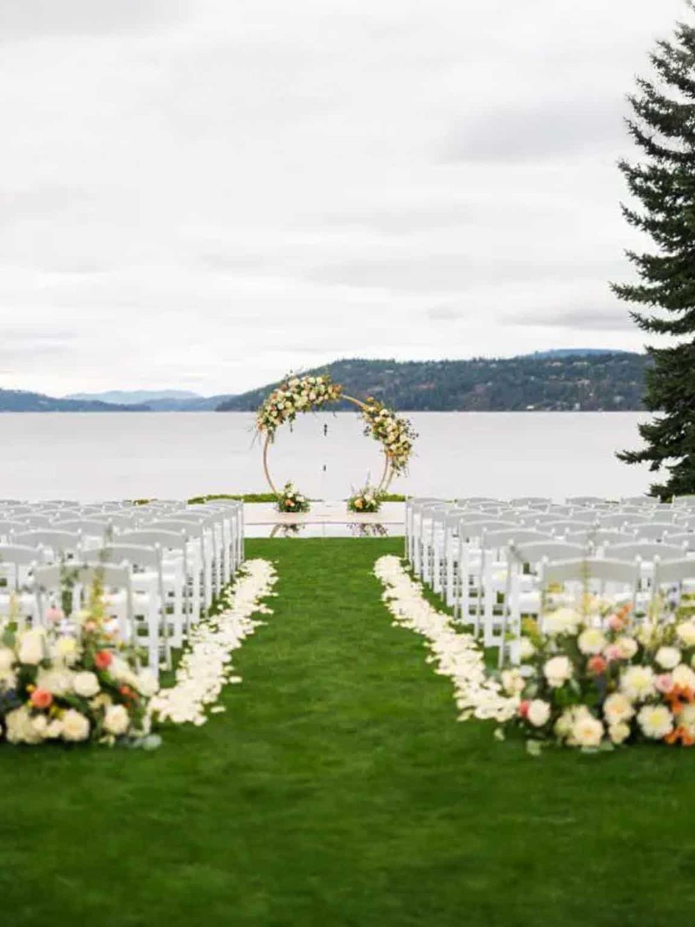 Lakeside wedding ceremony setup with floral decor, outdoor aisle, and scenic water view.