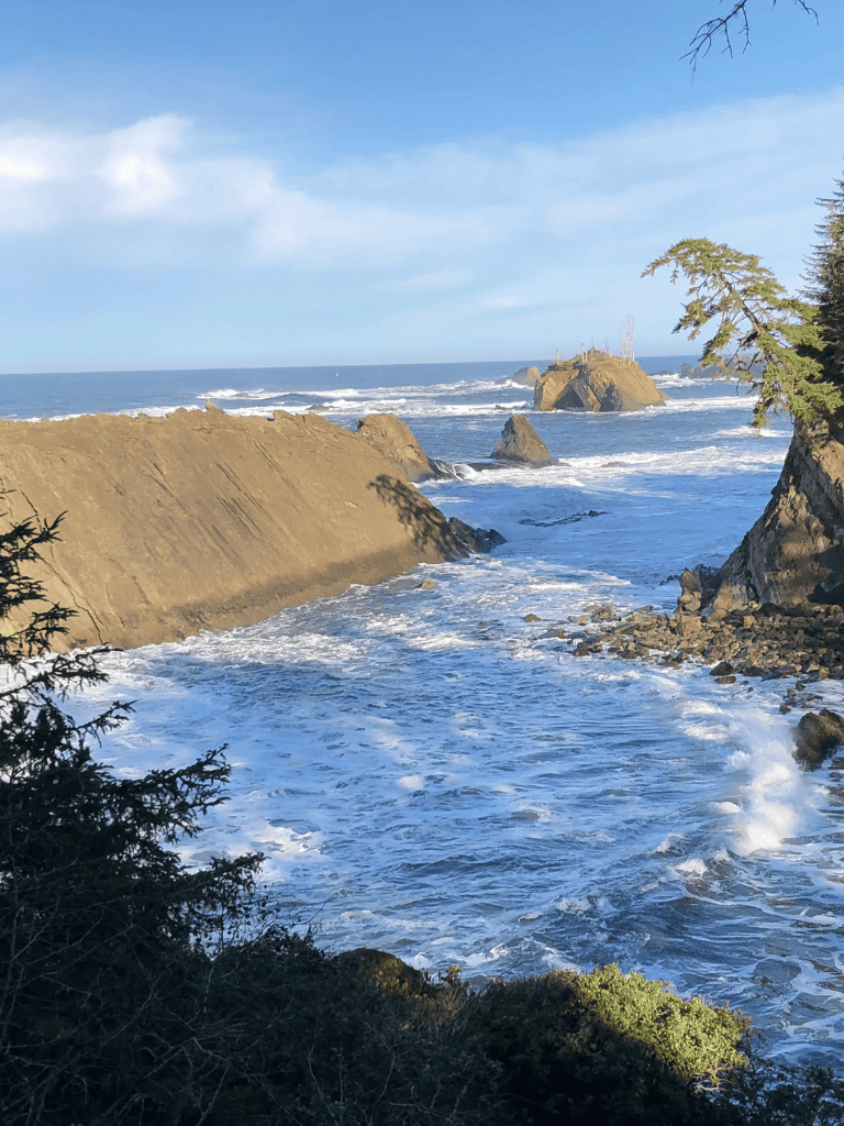 Stunning coastal view with rugged rocks, crashing waves, and lush trees, perfect for exploring Oregon's scenic coastline.
