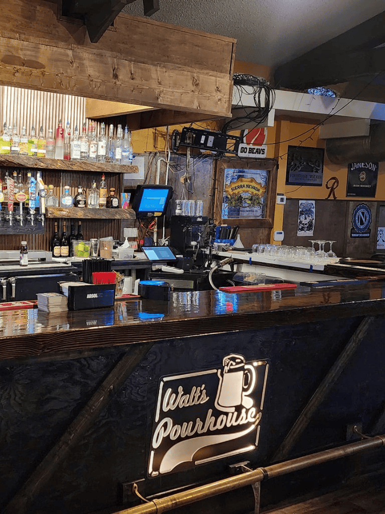 Friendly bar at Walton's Pourhouse with liquor bottles, taps, and bar equipment for regular customers.