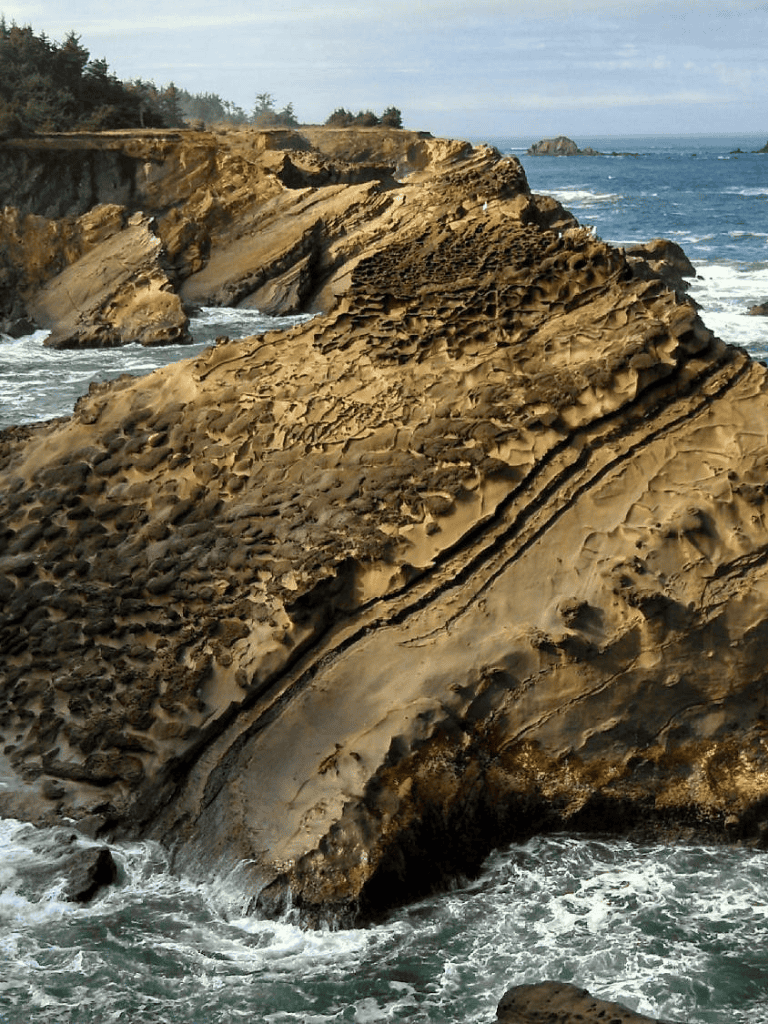 Vivid coastal rock formations along Oregon coastline with rugged textures and ocean waves.