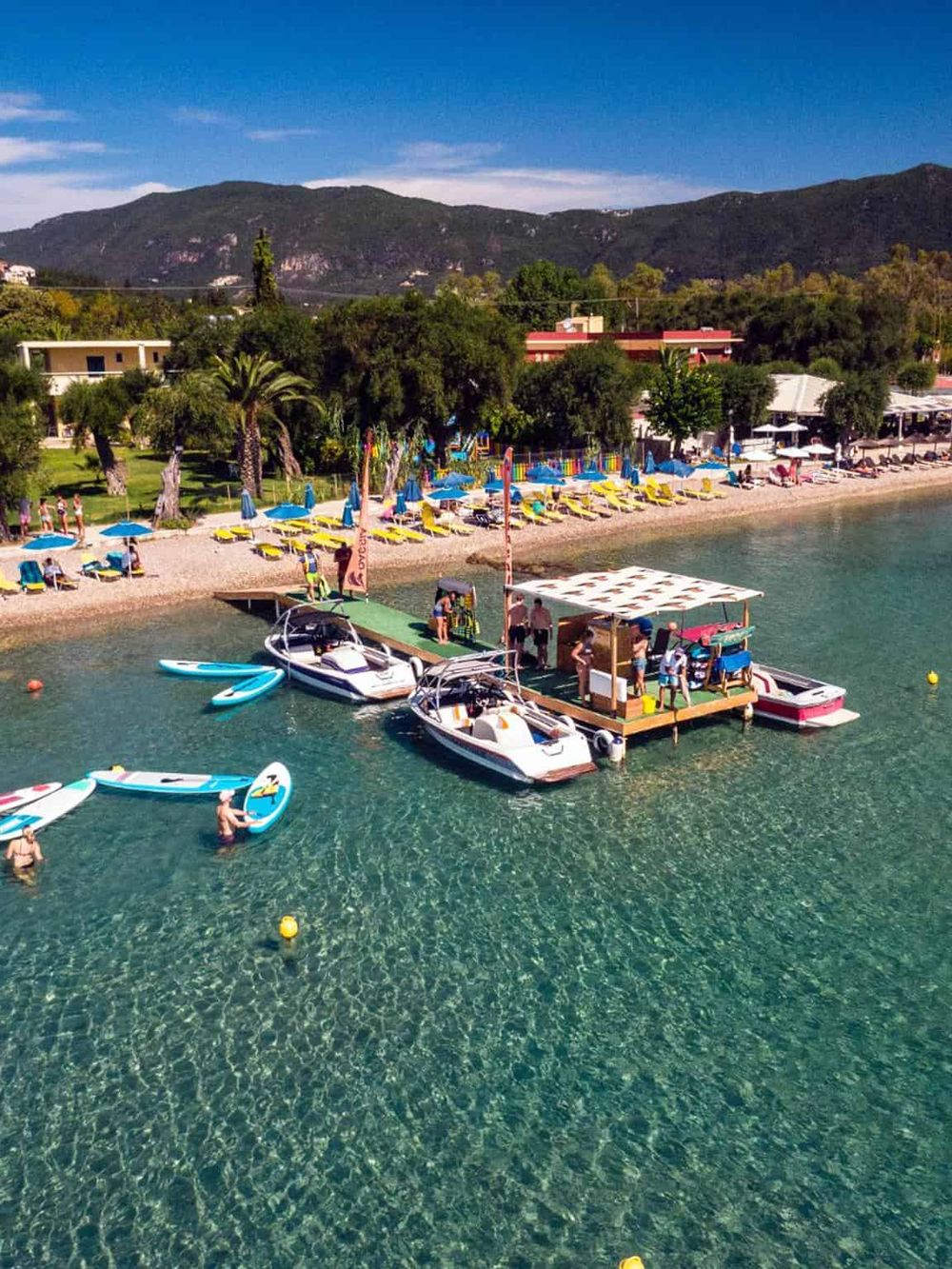 Vibrant beach with kayaks, paddleboards, and boats near scenic mountains in QuestForDirections.