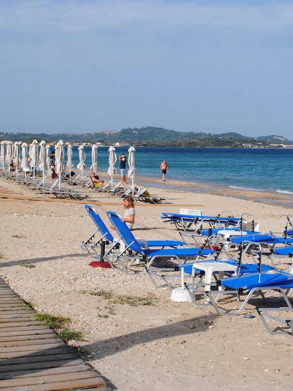 Bright beach with blue loungers and umbrellas, scenic views, perfect for relaxation and leisure.