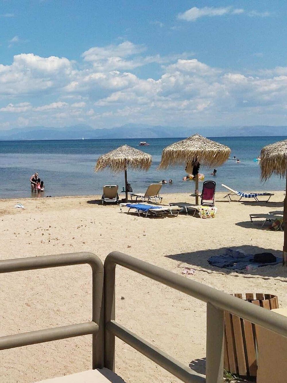 Relaxing beach with umbrellas, lounge chairs, and swimmers, perfect for vacation and leisure.