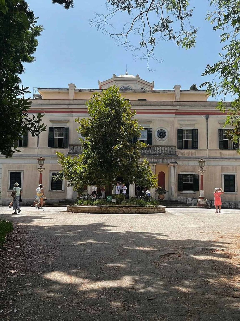 Charming historic building in Santa Barbara, with lush trees and visitors enjoying the outdoor space.