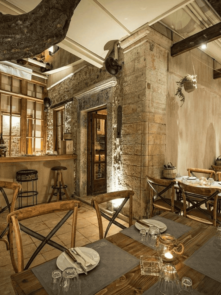 Cozy rustic restaurant interior with wooden tables, stone walls, and ambient lighting.