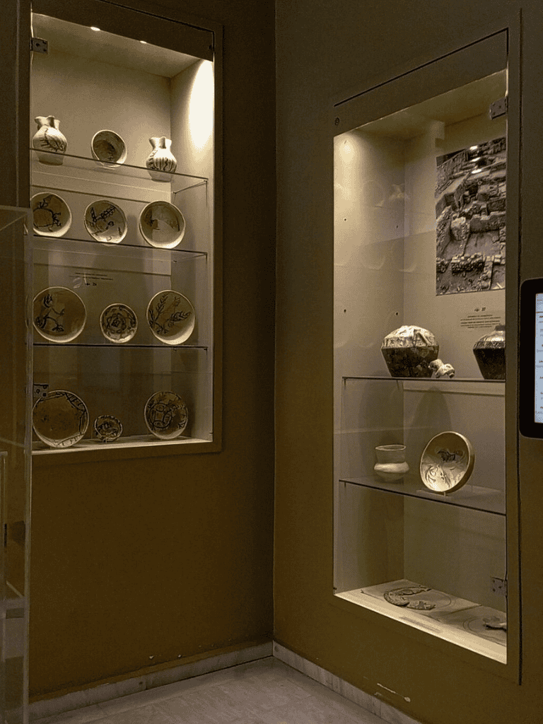 Ancient pottery display in museum glass case showcasing archaeological artifacts and historical ceramics.