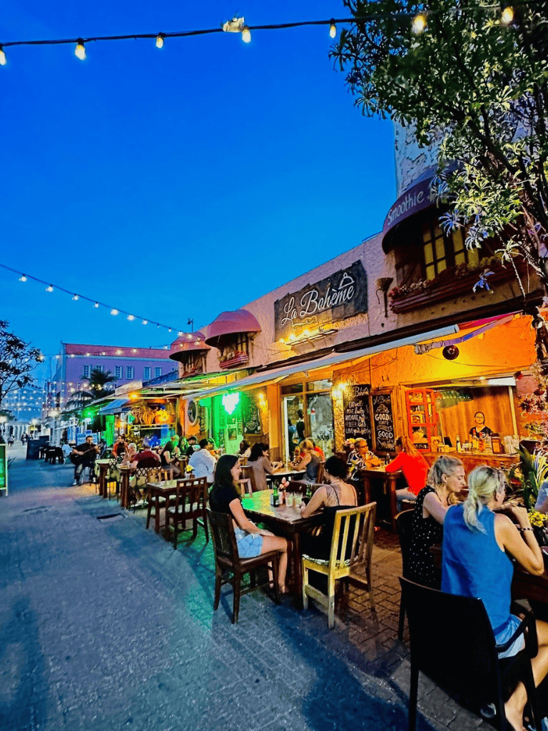 Al fresco dining at La Bohème restaurant with streetlights and outdoor seating, vibrant evening atmosphere.