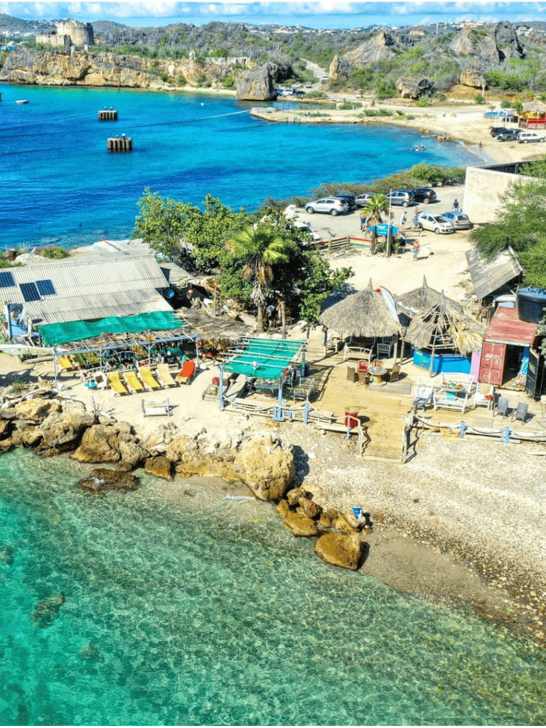 Colorful seaside cove with boats, huts, and clear turquoise water at QuestForDirections.
