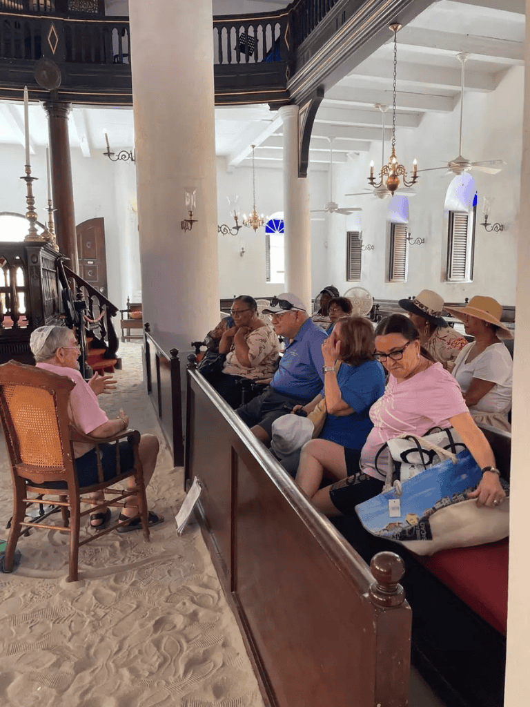 Historical church tour with guided instruction and diverse group of visitors inside a bright, historic Caribbean church.