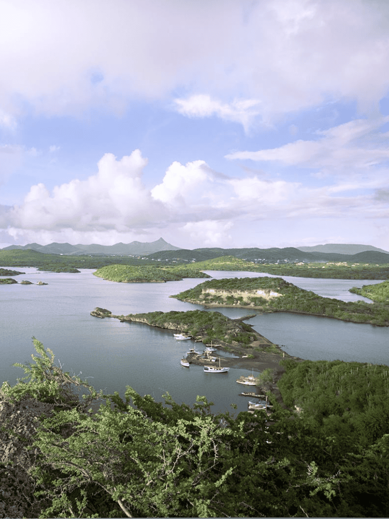 Vast landscape with islands, water, and boats under a partly cloudy sky, showcasing tropical scenery.