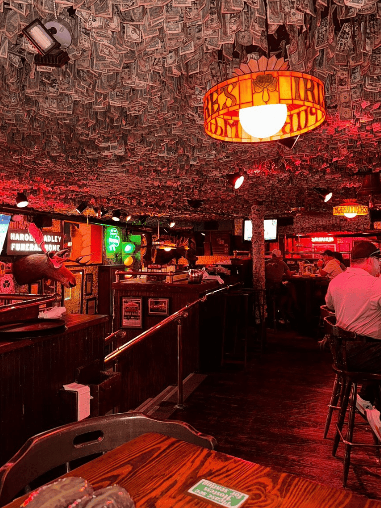 Colorful bar interior with dollar-note ceiling and neon signs, lively atmosphere at QuestForDirections.
