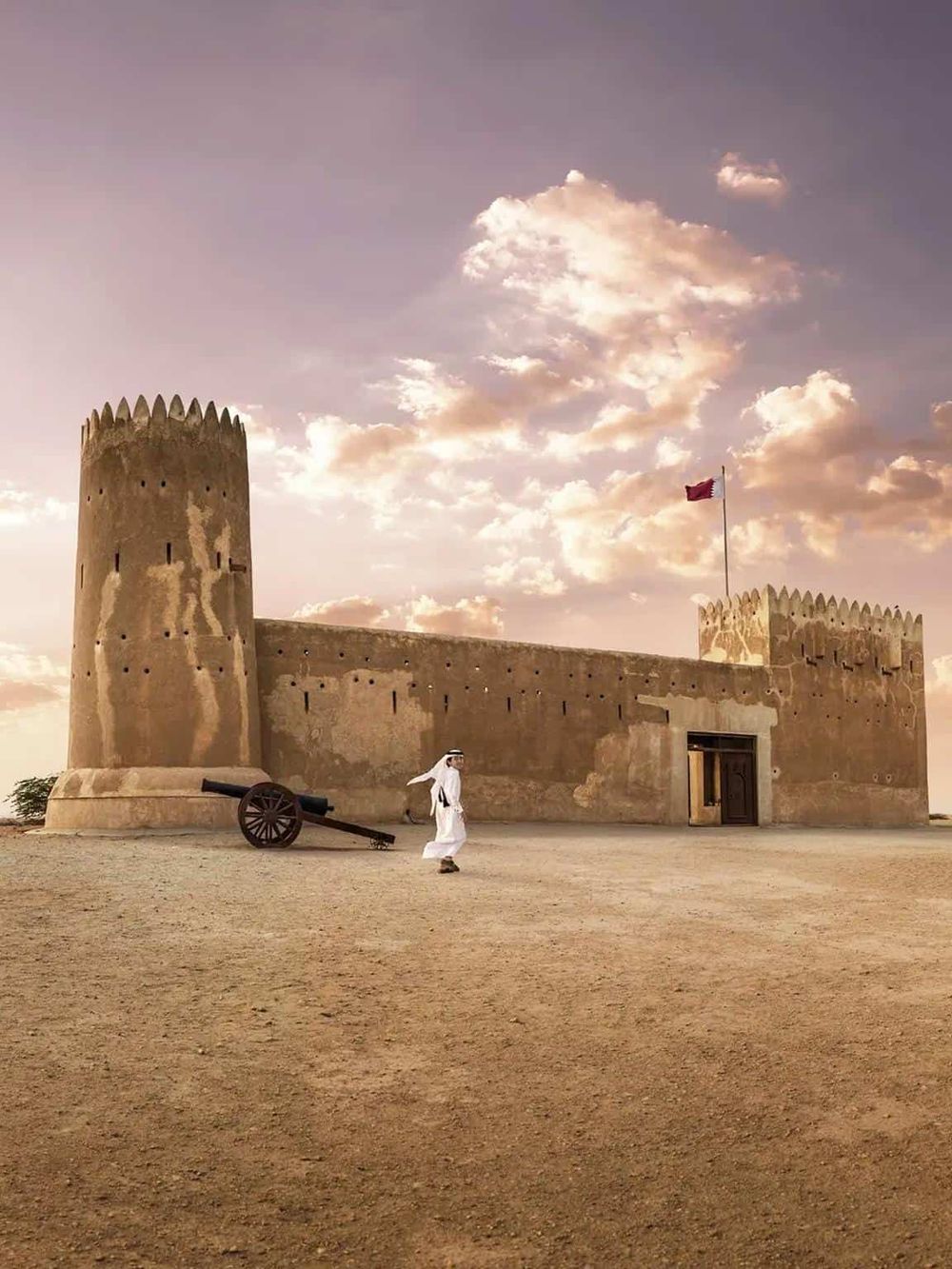 Ancient desert fortress with a guard and cannon, showcasing Middle Eastern architecture and history.