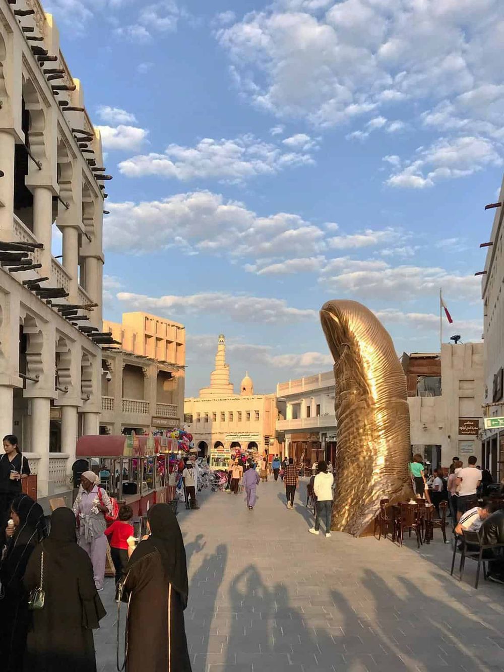 Modern shoppingstreet with sculptures and shops in search for directions.