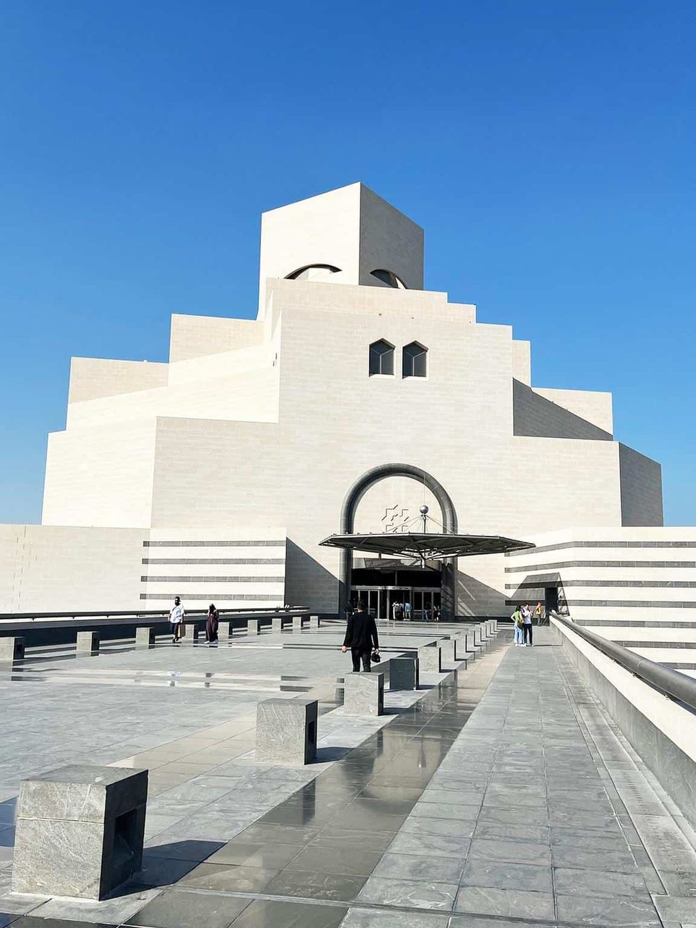 Modern architectural mosque with white exterior and geometric design, under a clear blue sky.