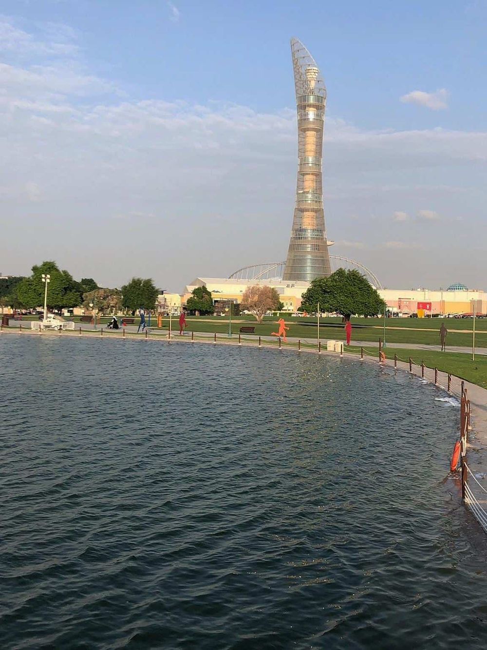 Modern skyscraper in a park by a water body in QuestForDirections city.