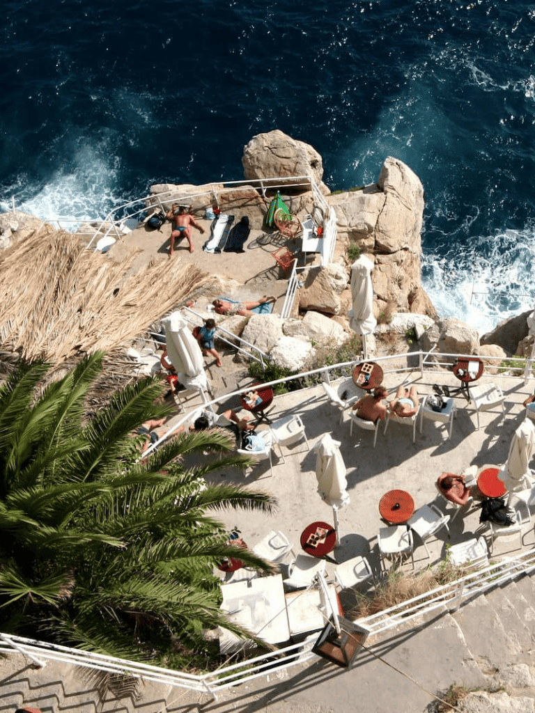 Relaxing oceanfront lounge with sunbathers, umbrellas, and scenic sea views at QuestForDirections resort.