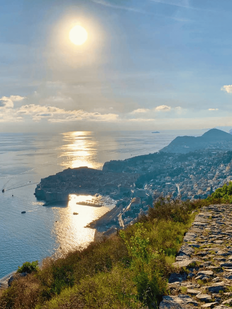 Vast ocean view with coastal city below and bright sun in clear sky, scenic landscape at QuestForDirections.