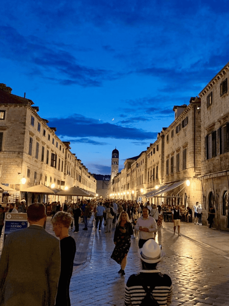 Vibrant evening street scene in historic Dubrovnik with lively crowd and beautiful architecture in Croatia.