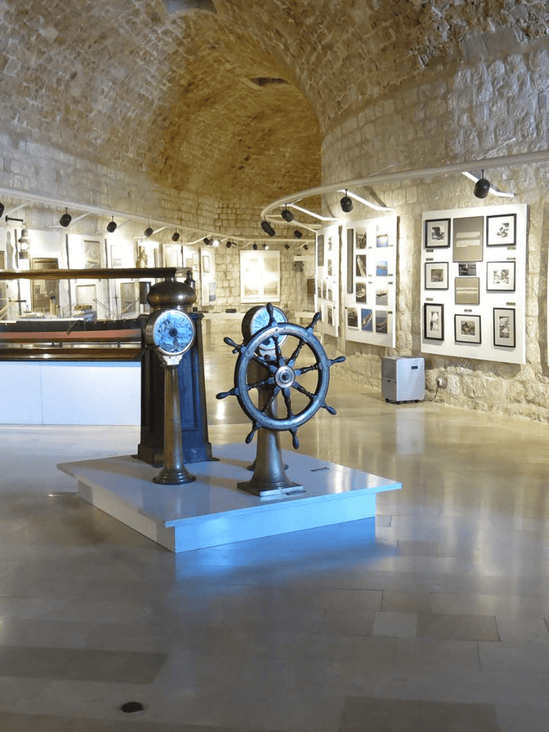 Steampunk ship wheel museum exhibit in historic stone gallery with artwork displays.