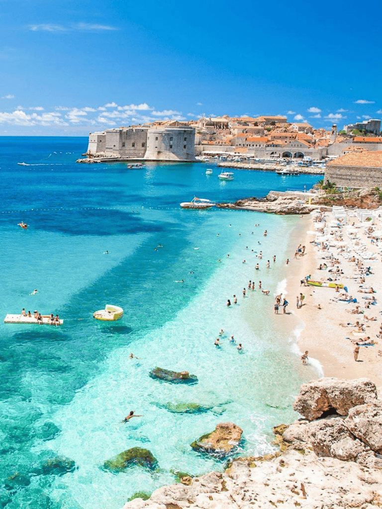 Bright turquoise beach with historic fortress and sunny seaside, perfect for travel and exploration.