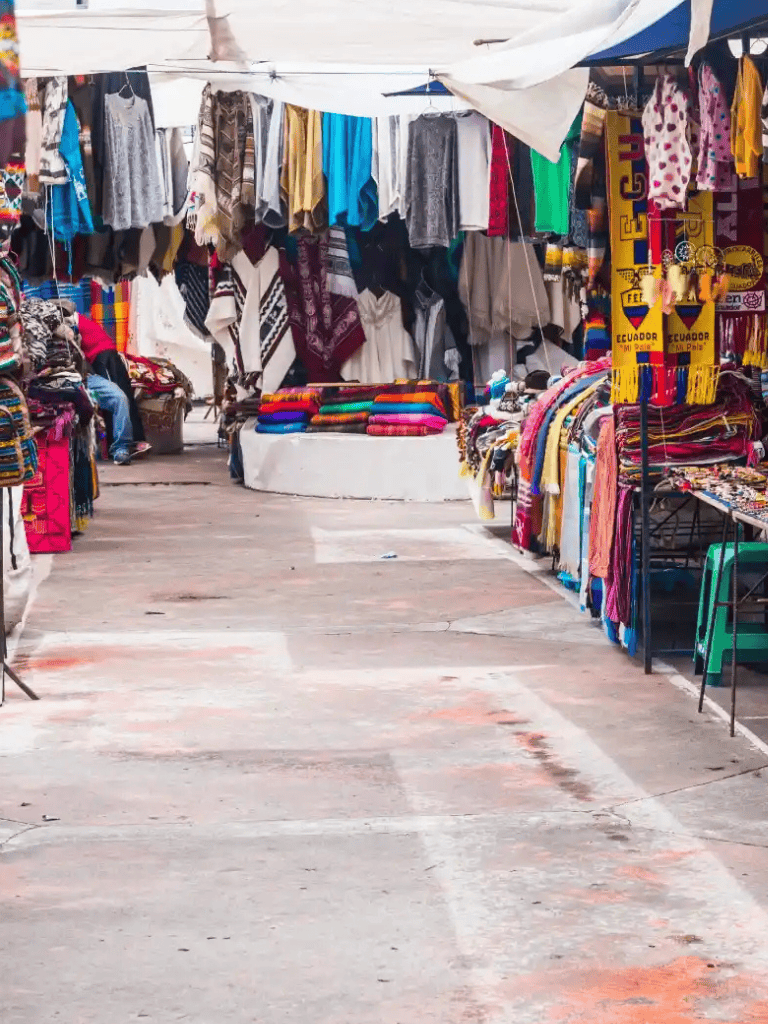 Colorful street market with clothing and textiles stalls in Ecuador, vibrant shopping experience.