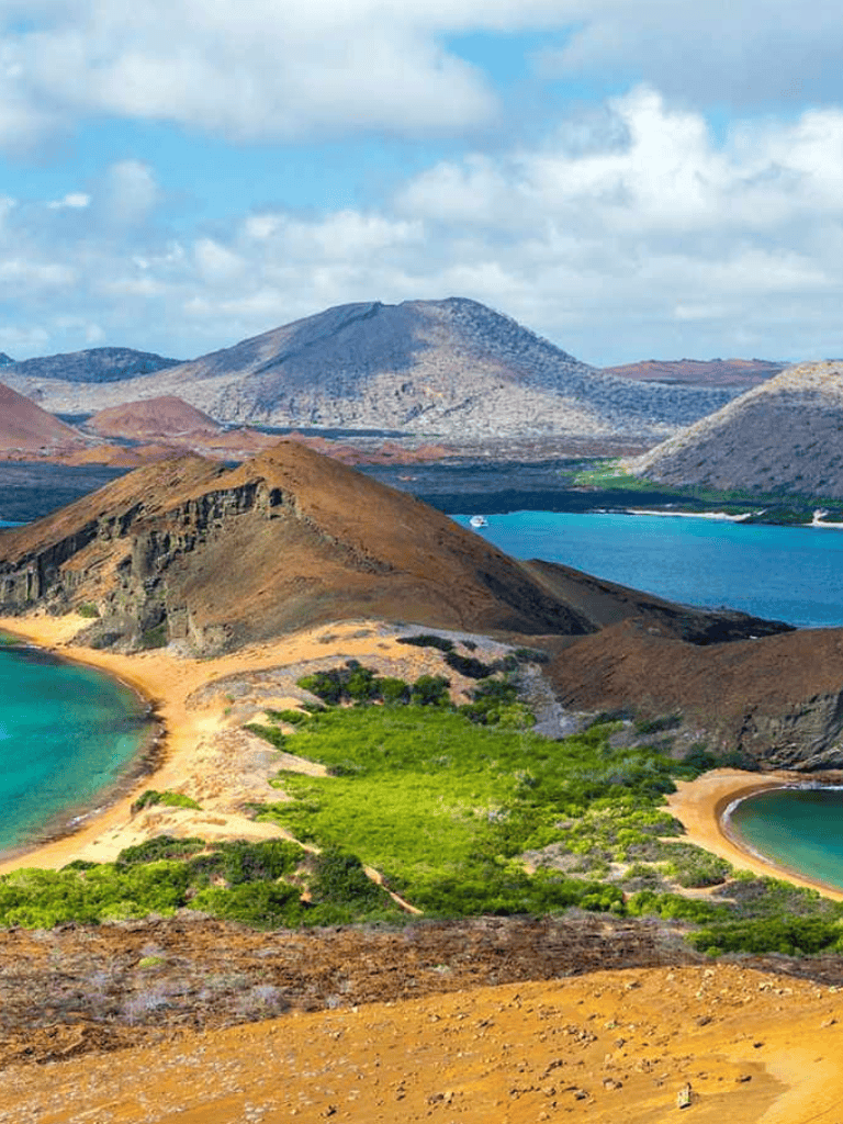 Vast volcanic landscape with colorful lakes and mountains in the background.