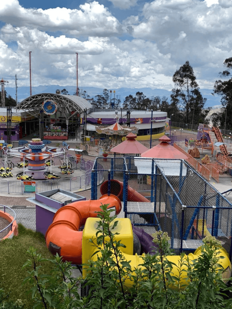 Water park with slides and amusement rides, surrounded by trees and cloudy sky, at QuestForDirections.