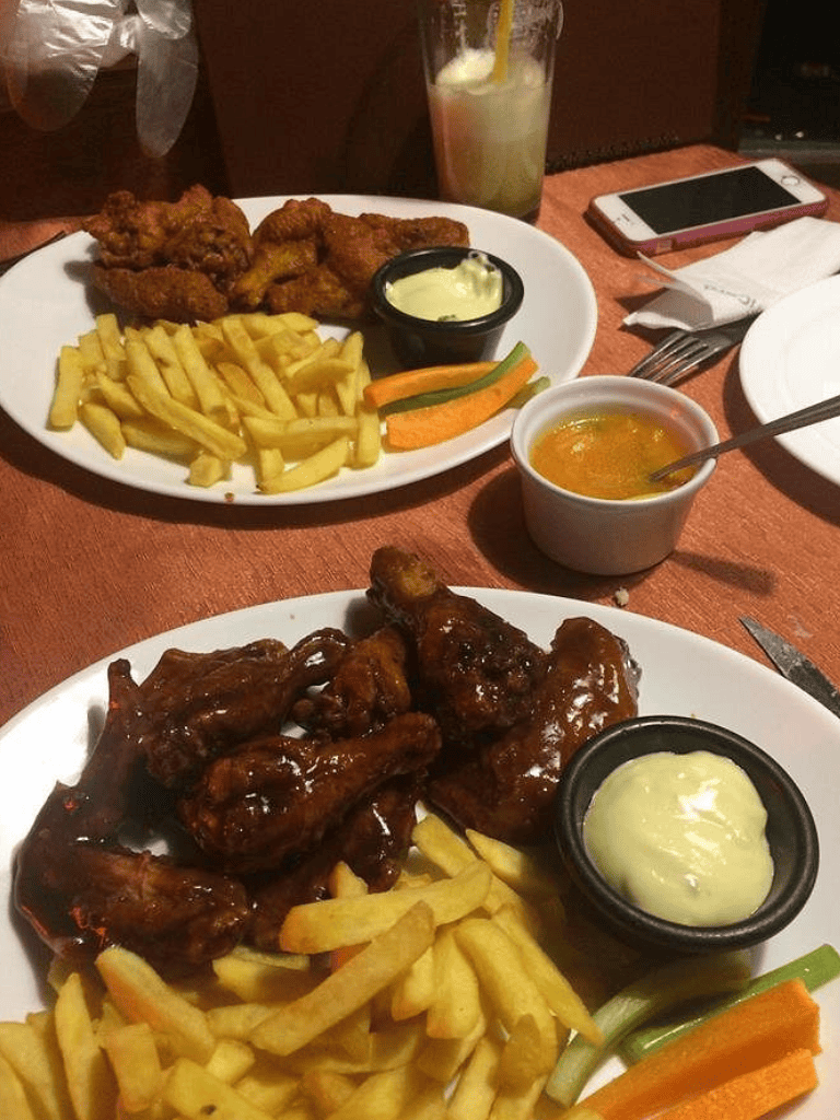Crispy fried chicken wings with fries and dipping sauces for a hearty meal.