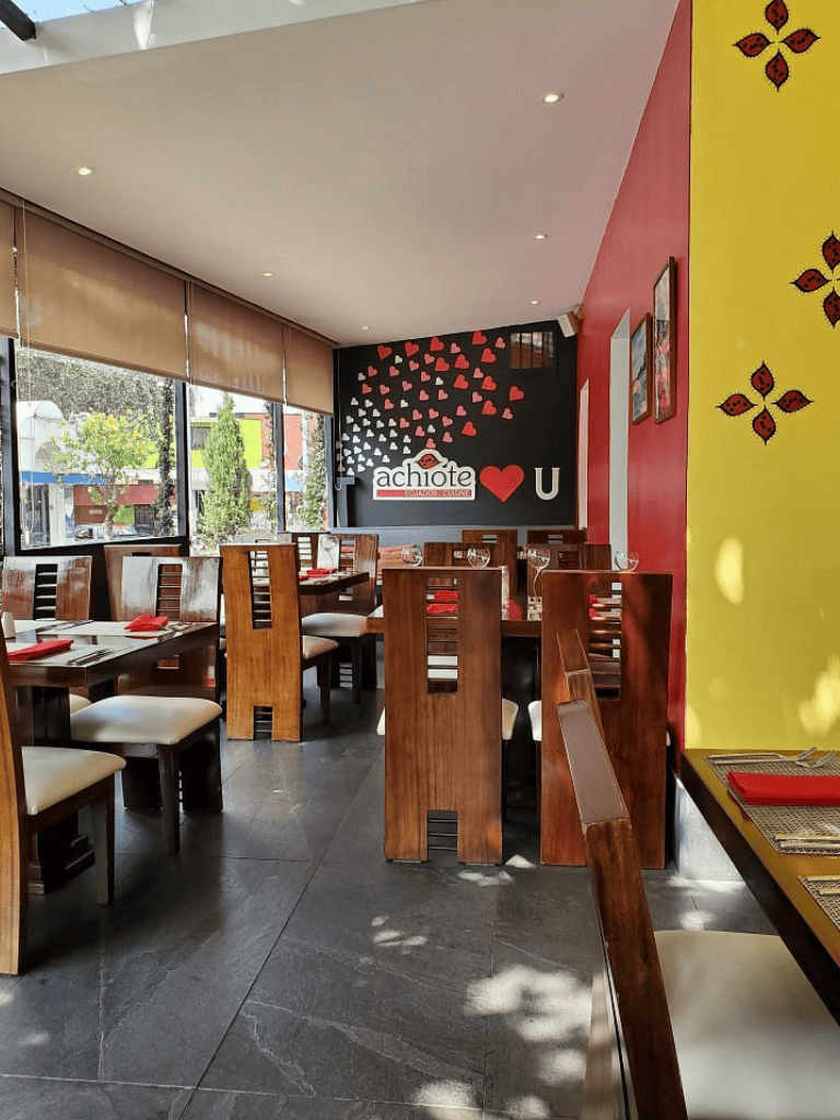 Cozy Ecuadorian restaurant interior with wooden tables and vibrant wall decor.