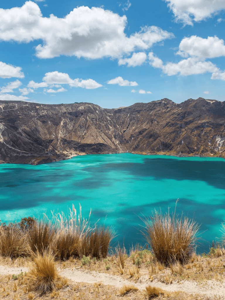 Vibrant turquoise lake with mountain backdrop and blue sky, scenic travel destination in New Zealand.