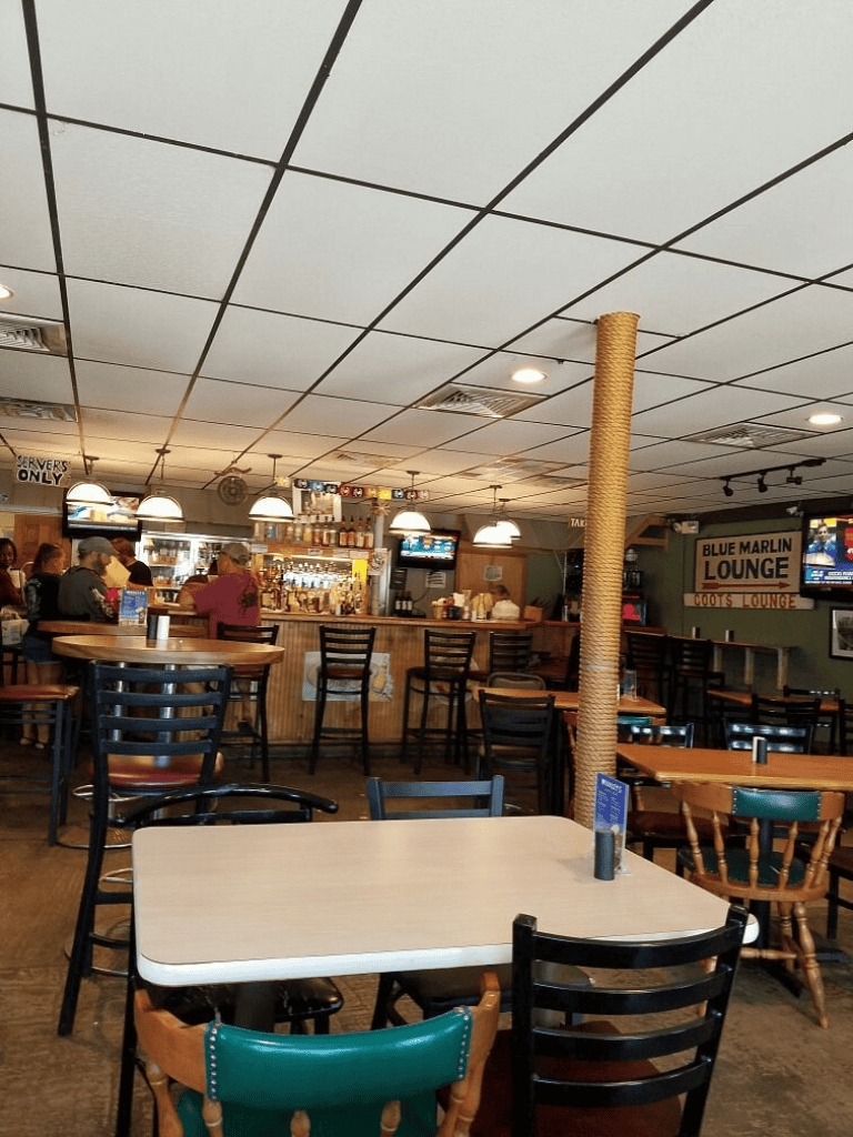 Sunny indoor bar with multiple tables, bar stools, and flat-screen TVs at Blue Marlin Lounge.