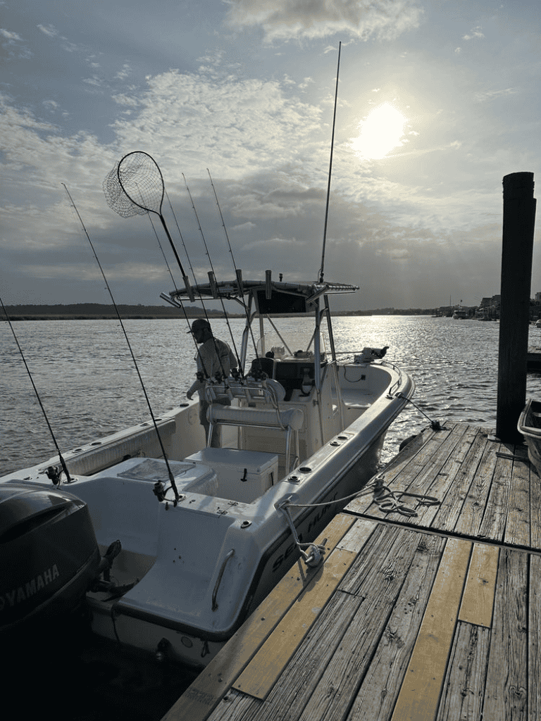 Boat with fishing gear docked at sunset on a river, ideal for fishing adventures and outdoor recreation.